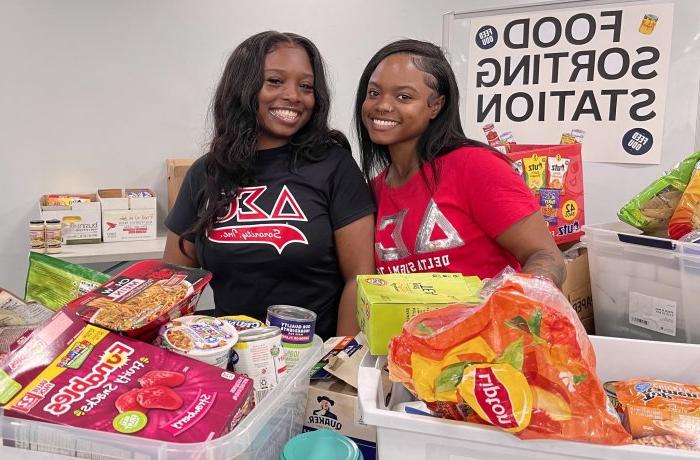 Two female students sort food items for donation.